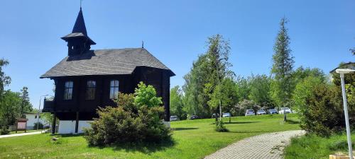 an old house with a steeple on a green field at Vila Kollár Apartmán 2 in Vysoke Tatry - Dolny Smokovec
