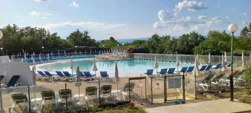 uma grande piscina com cadeiras e guarda-sóis em Duplex (5pers) dans village vacances en Ardèche em Grospierres