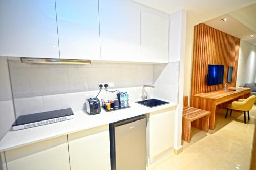 a kitchen with white cabinets and a sink and a desk at Pyramisa Hotel Apartments in Dubai