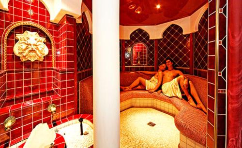 Dos personas tumbadas en una cama en un baño en Wellnesshotel Parkschlössl zu Thyrnau " Adults only" en Thyrnau