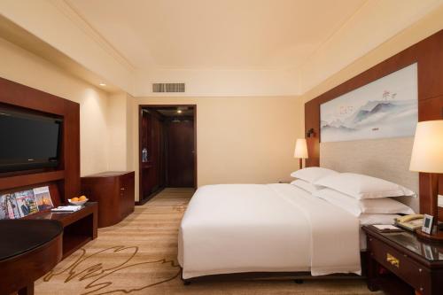 a hotel room with a bed and a flat screen tv at Shenzhen Sunshine Hotel, Luohu in Shenzhen