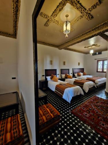 a bedroom with three beds and a large mirror at Riad Merzouga Dunes in Merzouga
