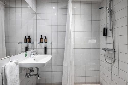 un bagno piastrellato bianco con lavandino e doccia di Airport Hotel, Billund a Billund