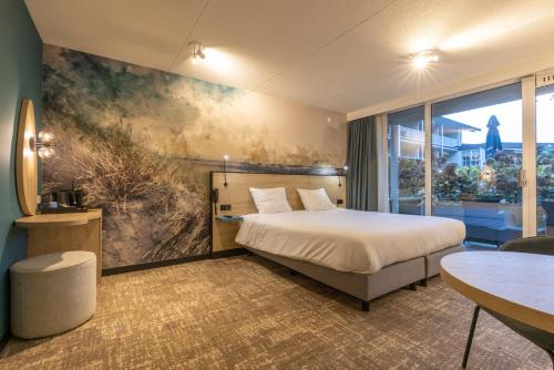 ein Hotelzimmer mit einem Bett und einem großen Fenster in der Unterkunft Fletcher Hotel Jan van Scorel in Schoorl