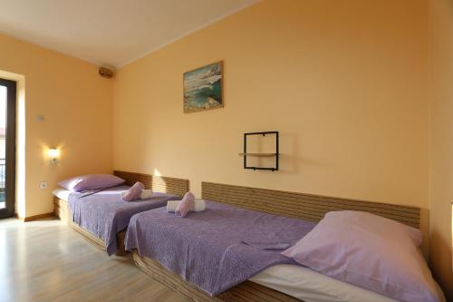 2 łóżka w pokoju z żółtymi ścianami w obiekcie House Zbasnik w mieście Klimno