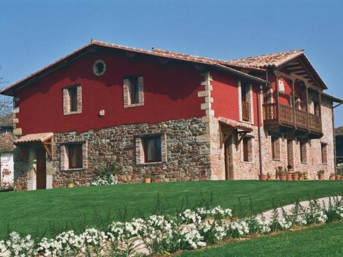 un gran edificio de ladrillo rojo con balcón. en Apartamentos Rurales El Mirador de Cazanes, en Cazanes