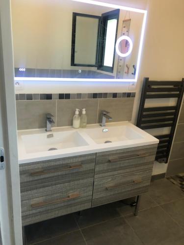 ein Badezimmer mit einem weißen Waschbecken und einem Spiegel in der Unterkunft Chambre privée à 10 min du circuit in Parigné-lʼÉvêque