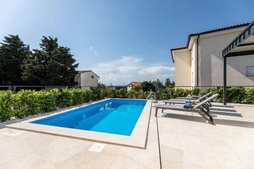 a swimming pool with a bench next to a house at Villa Bella in Klimno