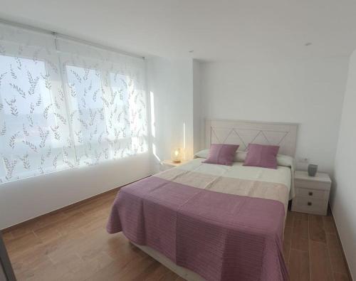 - une chambre blanche avec un grand lit et des oreillers violets dans l'établissement HyP - A casa da Fina, à Miño