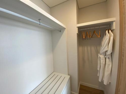 a walk in closet with a bed and white clothes at Roygent Parks Hai Phong in Hai Phong
