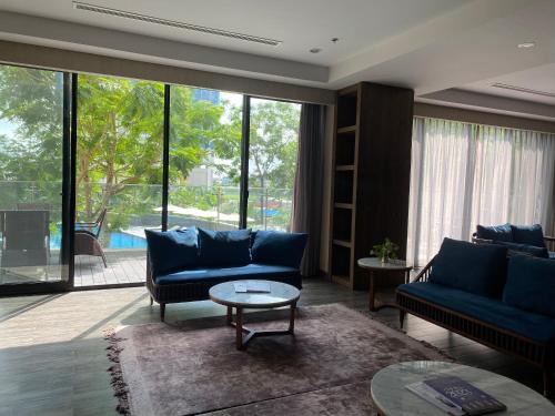 a living room with blue couches and a large window at Roygent Parks Hai Phong in Hai Phong
