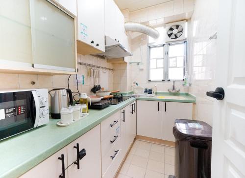 une cuisine avec des placards blancs et un comptoir vert dans l'établissement Student Accommodation - Lockhart Road 137, à Hong Kong