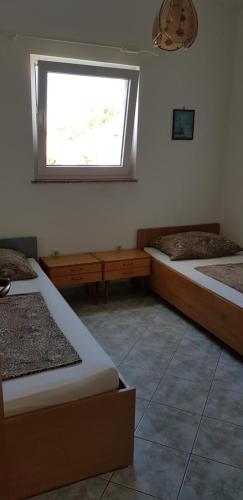 a room with two beds and a window at Apartments Vlasta in Karlobag