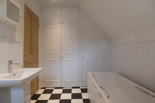 a white bathroom with a sink and a tub and a checkered floor at Little Burston in Dulverton