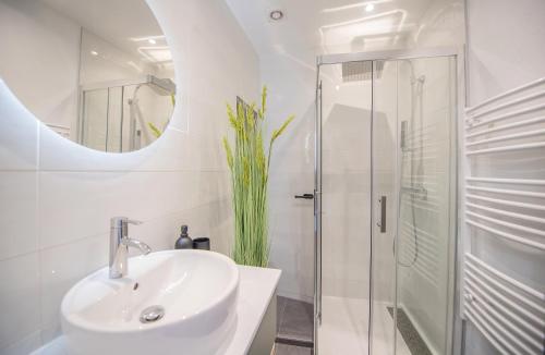 La salle de bains blanche est pourvue d'un lavabo et d'une douche. dans l'établissement 4 couchages aux pieds des musées - Parking et WiFi, à Grasse