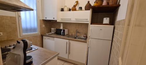 Elle comprend une petite cuisine avec des placards blancs et un réfrigérateur. dans l'établissement Appartement Toulon Centre-Ville, à Toulon