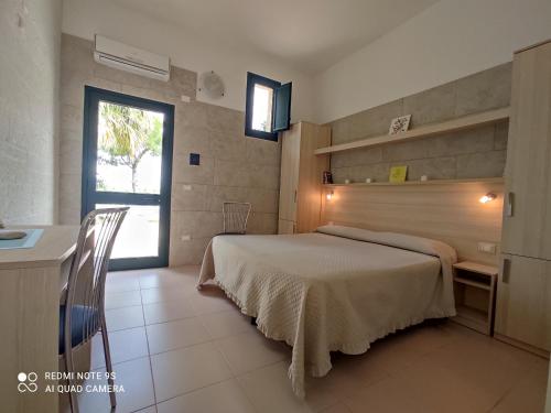 a bedroom with a bed and a table and a window at Masseria Don Egidio in Melendugno