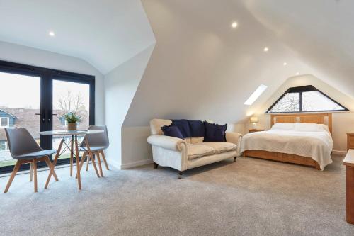 a bedroom with a bed and a chair and a table at The Lodge Bury St Edmunds in Bury Saint Edmunds