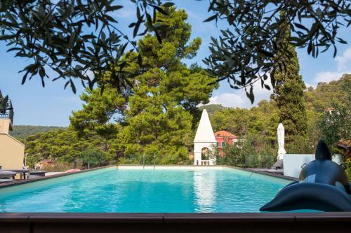 a swimming pool with a view of a church and trees at Hotel Fortuna in Hvar