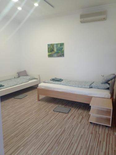 a bedroom with two beds and a wooden floor at Németh Vendégház -Torkos Fogadó in Ibrány