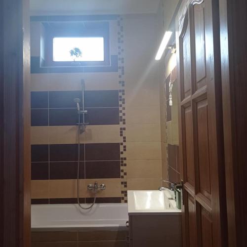 a bathroom with a tub and a sink and a window at Németh Vendégház -Torkos Fogadó in Ibrány