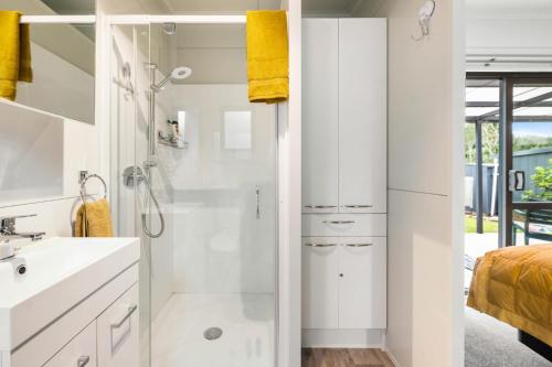 a white bathroom with a shower and a sink at Birdsong - Turangi Holiday Unit in Turangi