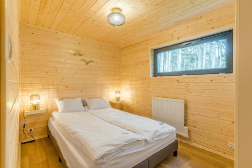 1 dormitorio con 1 cama en una cabaña de madera en Bursztynowo, en Kąty Rybackie