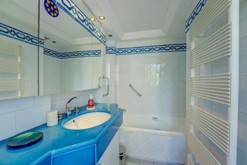 La salle de bains est pourvue d'un lavabo bleu et d'une baignoire. dans l'établissement New Listing - Amazing Beach Views, 1-bed Apt, à Cannes