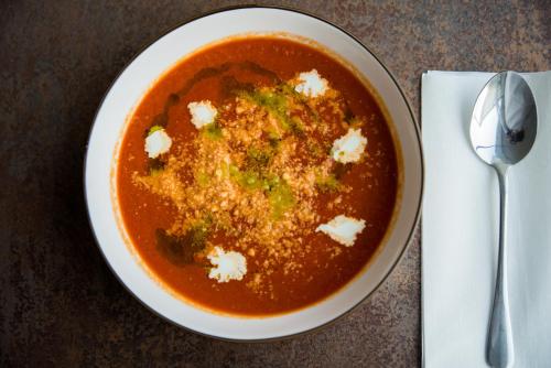 a bowl of tomato soup on a table with a spoon at Penzion Troja in Lipany