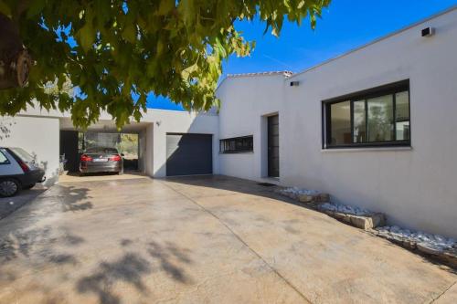 une maison blanche avec une voiture garée dans une allée dans l'établissement L'élixir - Architect villa & Heart of Provence, à Flayosc
