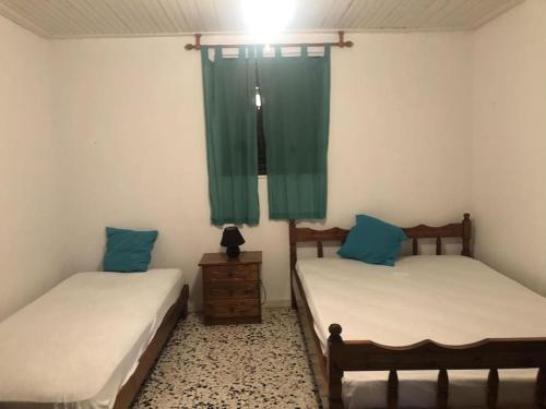2 Betten in einem Zimmer mit grünen Vorhängen in der Unterkunft Summer beach house Spiaggia in Katarrákhion