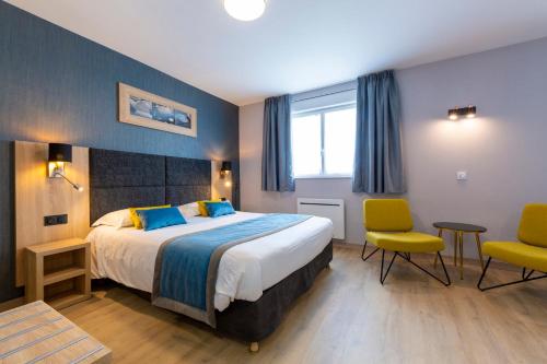 um quarto de hotel com uma cama grande e duas cadeiras em Hôtel L'Escale - Piscine & SPA em Escalles