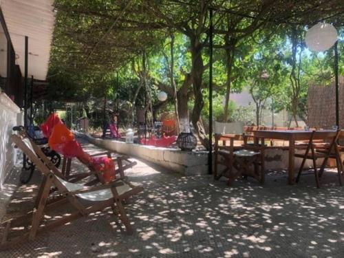 eine Terrasse mit Stühlen, einem Tisch, einem Tisch und Bäumen in der Unterkunft Summer beach house Spiaggia in Katarrákhion