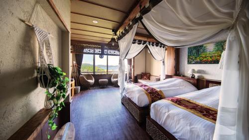 鳥羽市にあるBali Resort SAYA no Kazeのベッド2台と窓が備わるホテルルームです。