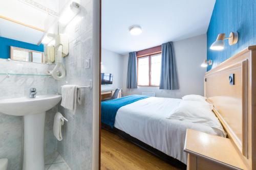 a bathroom with a bed and a sink in a room at Hôtel L'Escale - Piscine & SPA in Escalles