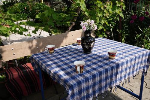 a table with a vase of flowers and cups on it at Etnobubi in Novi Sip