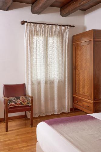 a bedroom with a bed and a chair and a dresser at Agriturismo Rechsteiner in Ponte di Piave