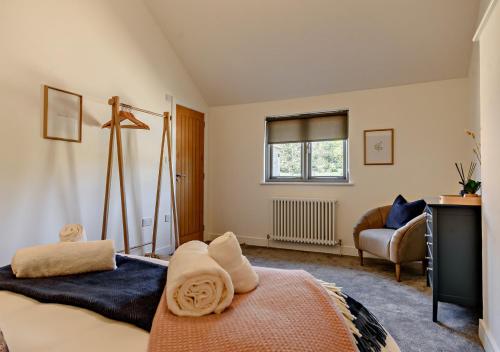 a bedroom with a bed and a chair and a window at Clerks Cottage in Letheringsett