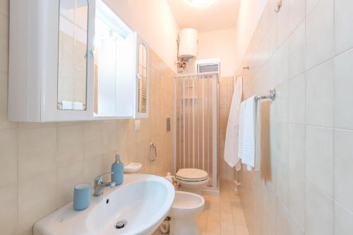 a white bathroom with a sink and a toilet at Casa Blu in Castellammare del Golfo