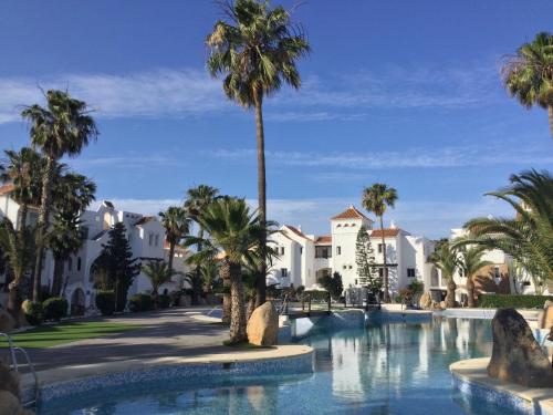 a resort pool with palm trees and buildings at La Perla Azul - Terraza panorámica al Sol in Roquetas de Mar