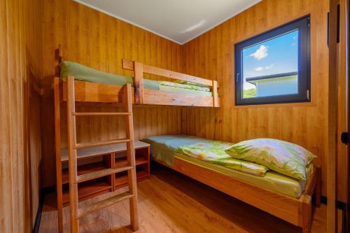 a bedroom with two bunk beds and a window at Domki drewniane na Spławiu nad morzem in Darłowo