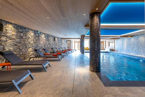 a pool with lounge chairs and a stone wall at La Cour aux Ecureuils in Peisey-Nancroix