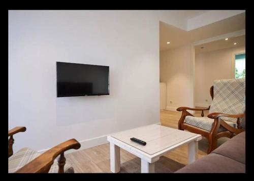 ein Wohnzimmer mit einem Sofa und einem TV an der Wand in der Unterkunft Acogedor y precioso apartamento + parking privado in San Sebastián