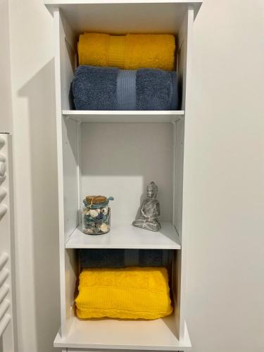 un placard blanc avec des serviettes jaunes et bleues dans l'établissement Studio Neuf à 10min Plage & Centre-Ville + Garage, à Ajaccio