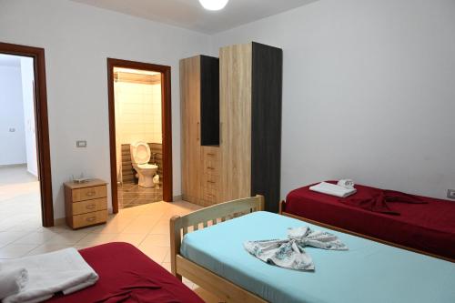 a bedroom with two beds and a bathroom with a toilet at Iris apartaments in Sakës