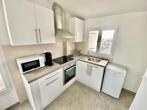 a small kitchen with white cabinets and a microwave at Chez Frederic in Marseille