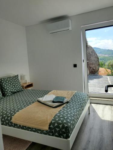 a bedroom with a bed with a large window at Douro Mesio Guest House in Resende