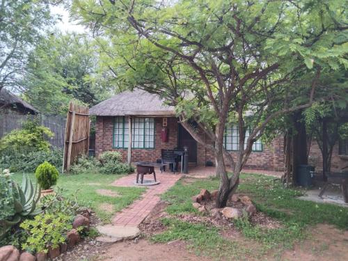 a brick house with a tree in the yard at Tranquillity Day Spa & Lodge in Baviaanspoort