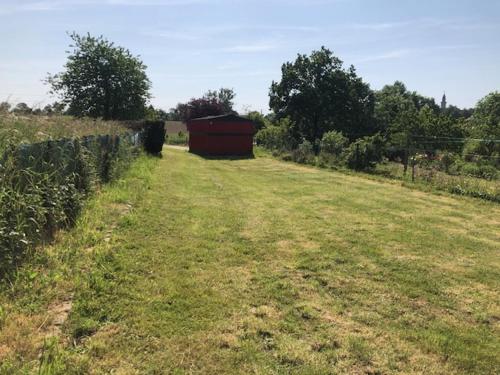 a field with a red barn in the middle of it at LE GRILLOU in Couterne