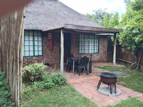 a brick house with a table and a grill in the yard at Tranquillity Day Spa & Lodge in Baviaanspoort